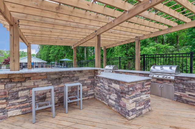 Outdoor grilling area with two built-in grills and a stone-faced counter with bar stools.
