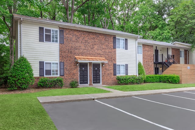 Exterior of apartment building with brick and siding, featuring multiple entrances and parking.