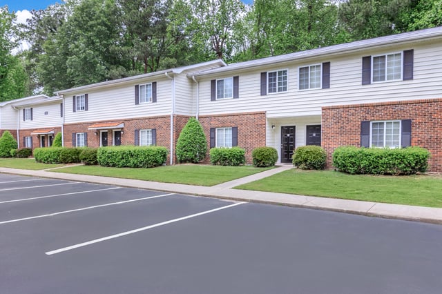 Exterior of apartment buildings with parking lot in foreground.