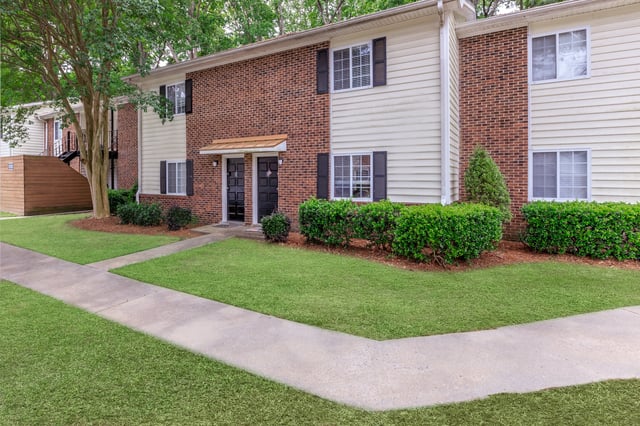 Exterior of apartment buildings with brick and siding, two front doors, and a sidewalk.