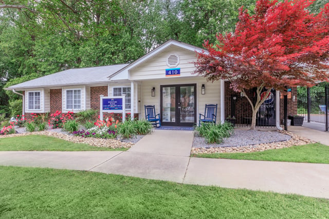 Office building entrance with rocking chairs and landscaping.