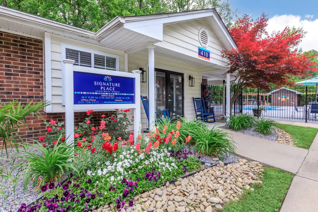 Signature Place apartment building exterior with signage and landscaping.