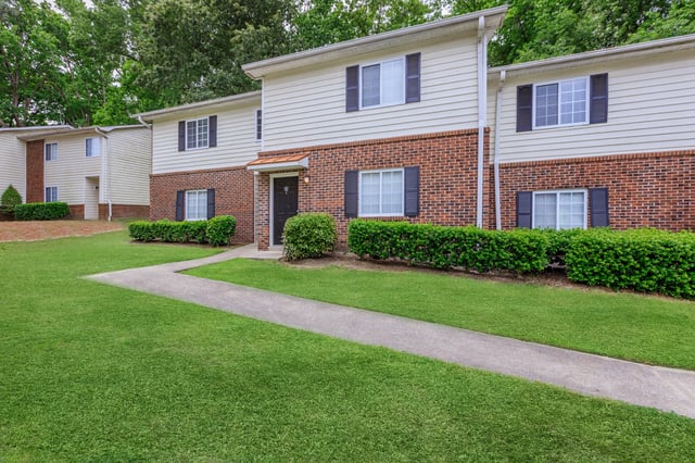 Exterior view of apartment buildings with manicured lawns and walkways.