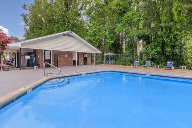 Swimming pool with lounge chairs and a small building.