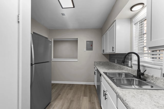 Modern kitchen with stainless steel refrigerator, white cabinets, and granite countertops.