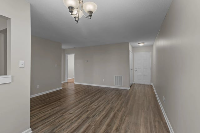 Empty living room and entryway with wood-look flooring and neutral walls.