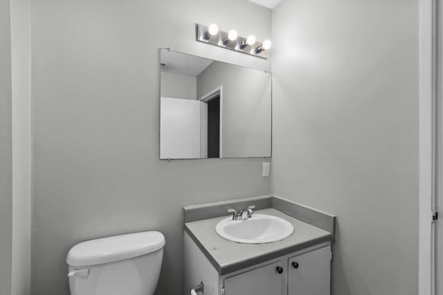 Bathroom with toilet, vanity, and mirror.