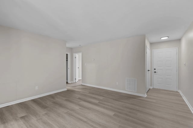 Interior view of a vacant apartment unit showing wood-look flooring and white doors.