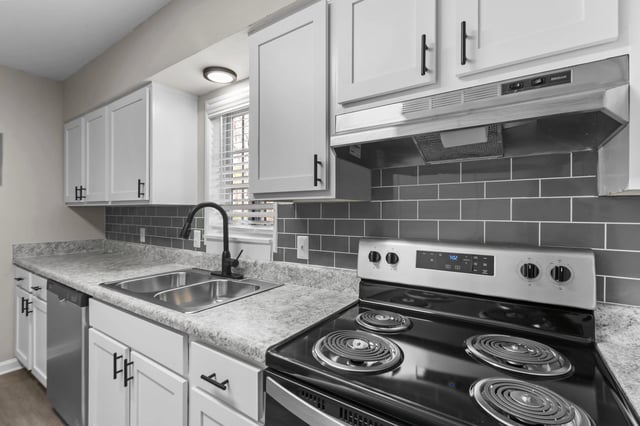 Modern kitchen with white cabinets, gray subway tile backsplash, and stainless steel appliances.