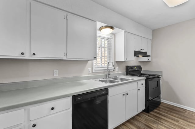 Modern kitchen with white cabinets, stainless steel sink, black stove, and dishwasher.