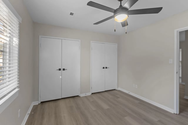 Empty bedroom with two closets and a ceiling fan.