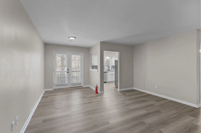 Spacious living room with natural light and access to kitchen.