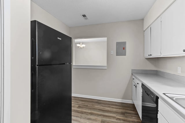 Modern kitchen with black refrigerator and white cabinets