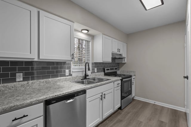Modern kitchen with white cabinets, grey subway tile backsplash, stainless steel appliances, and granite countertops.