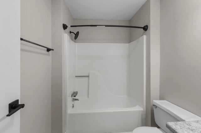 Modern bathroom with a white bathtub, shower, and toilet.
