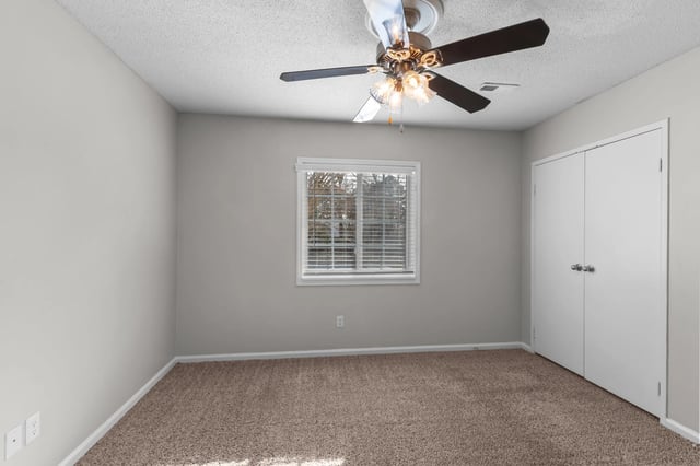 Empty bedroom with a ceiling fan and closet.