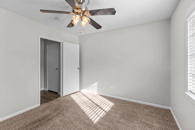 Bedroom with ceiling fan and window blinds.