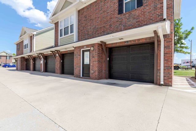 Exterior view of apartment building with garages and light post.