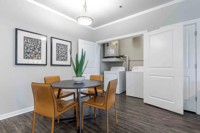 Dining area with chairs and a table, adjacent to a laundry closet with washer and dryer.