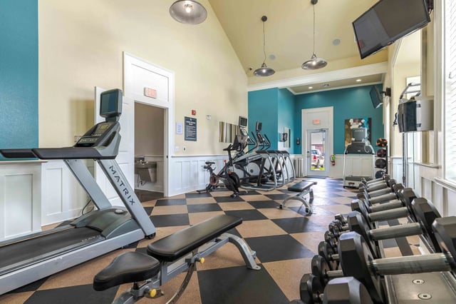 Fitness center with treadmills, ellipticals, stationary bikes, free weights, and benches.