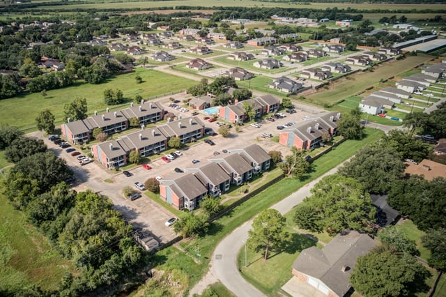 Aerial view of apartment buildings, surrounding houses, and a swimming pool.