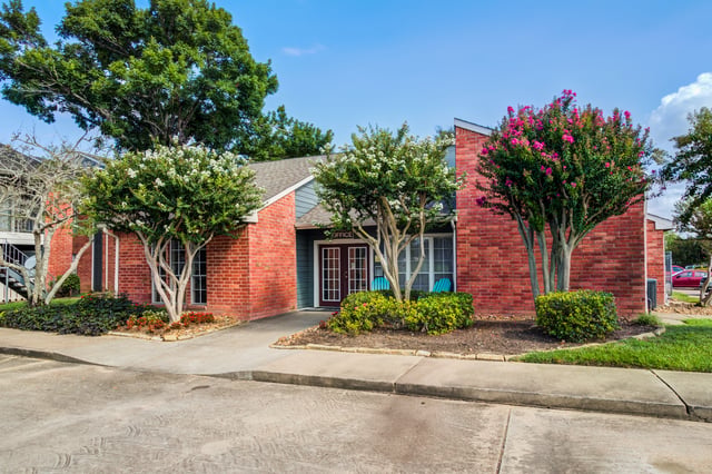 Office building entrance with red brick exterior and manicured landscaping.