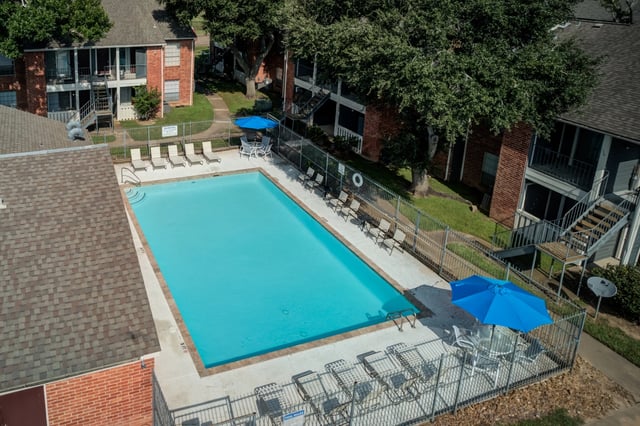 Aerial view of a bright blue swimming pool with lounge chairs and umbrellas.