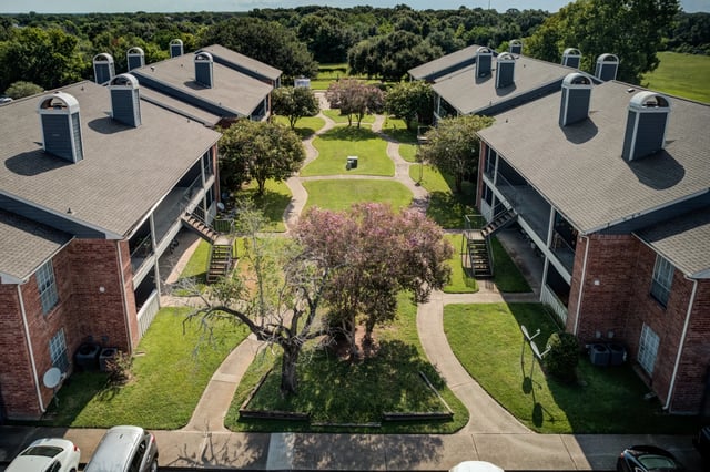 Aerial view of apartment buildings with central courtyard and walking paths.