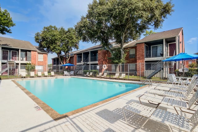 Swimming pool with lounge chairs and umbrellas at a multifamily property.