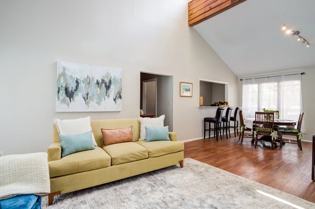 A view of the living room, dining area, and kitchen bar seating.