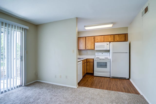 Kitchen area with white appliances and wooden cabinets.