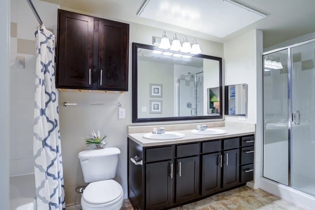Modern bathroom with double vanity, large mirror, and glass-enclosed shower.