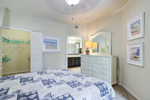 Bedroom with a queen-size bed, dresser, closet, and en-suite bathroom.
