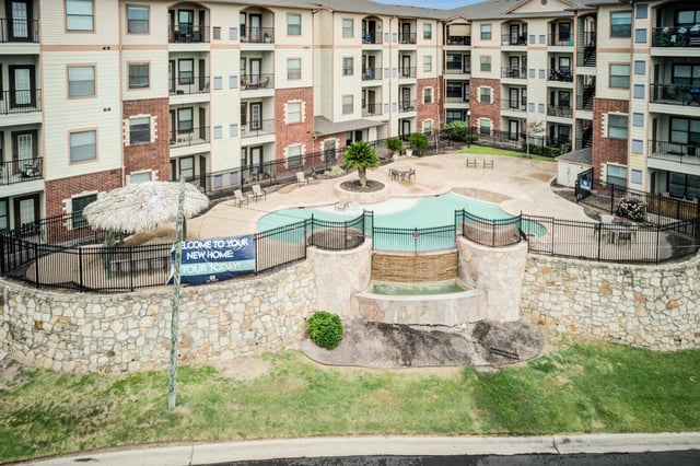 Apartment complex exterior with a swimming pool and waterfall feature.