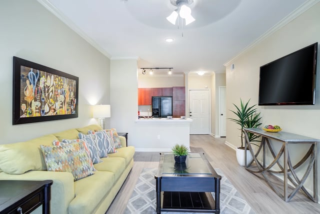 Living room with sofa, coffee table, TV, and kitchen visible.