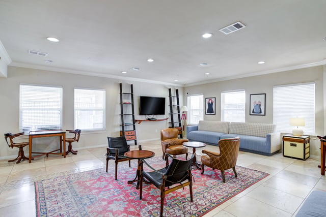 Community lounge area with comfortable seating, a TV, and decorative art.