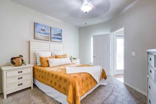 Cozy bedroom with a king-size bed, plush carpet, and beach-themed artwork.
