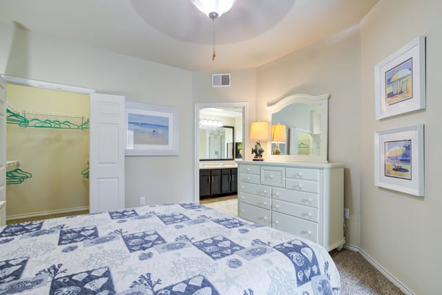 Bedroom with a large bed, dresser, and closet.