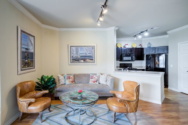 Living room and kitchen area with sofa, chairs, coffee table, and kitchen appliances.