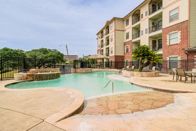 Sparkling outdoor swimming pool with lounge chairs and a thatched-roof cabana.