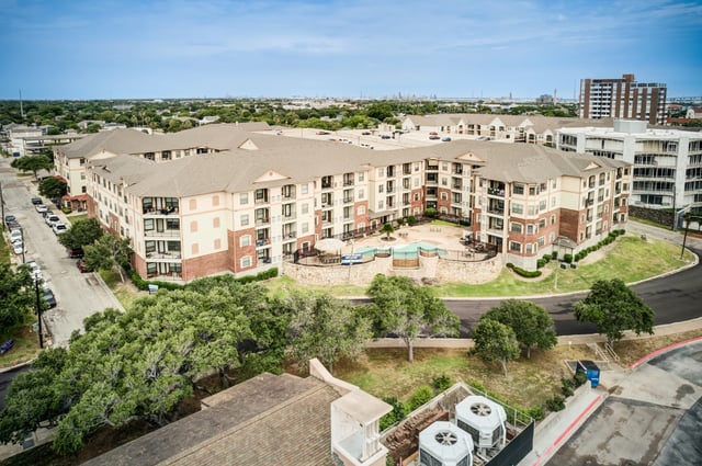 Apartment building exterior with courtyard and swimming pool.