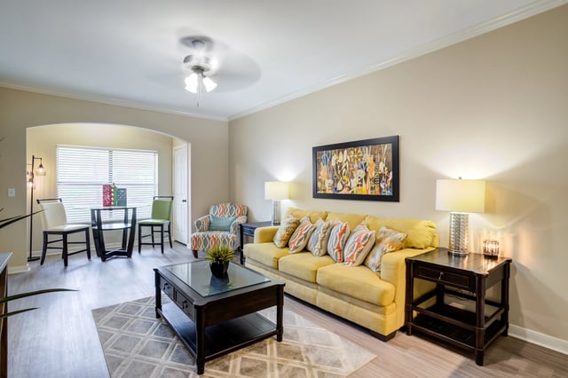 Living room with a yellow sofa, coffee table, and dining area.