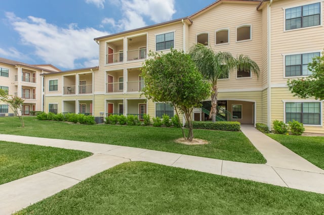 Exterior view of apartment buildings with balconies and green lawns.