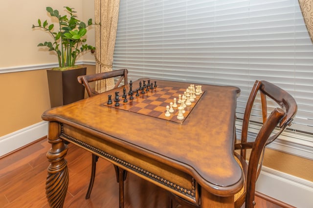A chess table with chess pieces set up and two chairs