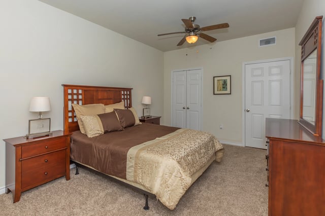 Primary bedroom with a queen-size bed, nightstands, dresser, and ceiling fan.