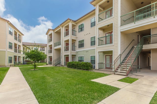Exterior view of apartment buildings with green lawns and walkways.
