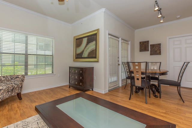 Living and dining area with a large window, accent chair, dresser, and dining table.