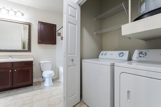 Bathroom with vanity, toilet, and in-unit washer and dryer.
