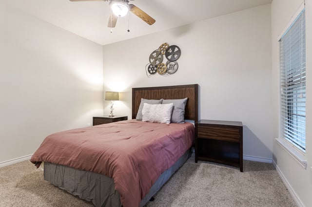 Bedroom with a queen-size bed, bedside tables, and a ceiling fan.