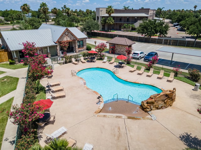 Aerial view of a resort-style swimming pool with lounge chairs and umbrellas.